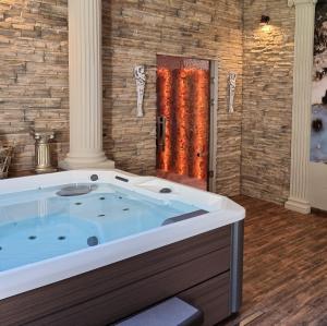 a jacuzzi tub in a room with a brick wall at Dworek za Lasem in Warta