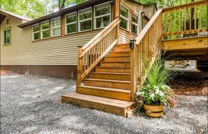 a house with a wooden staircase and a potted plant at The Nook Lodge - cabin with hot tub at Shawnee and Camelback Mtn in East Stroudsburg