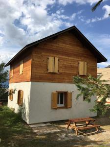 una pequeña casa con una mesa de picnic delante de ella en Chalet 6 personnes Gentiane en Les Orres