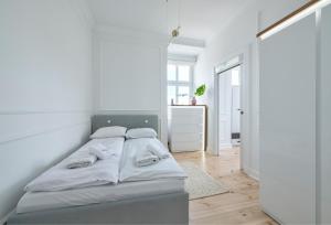 a white bedroom with a bed with white walls at Dom & House - Apartment Golden Loft Sopot in Sopot