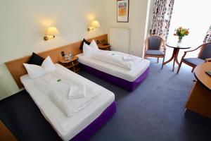 ein Hotelzimmer mit 2 Betten, einem Tisch und Stühlen in der Unterkunft Hotel Garni Am Schäfersberg in Niedernhausen
