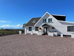 a white house with a gravel driveway at Self Catering Spacious open plan 3 bed apartment with sea views in South Erradale