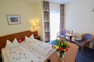 ein Hotelzimmer mit einem Bett und einem Tisch mit Blumen darauf in der Unterkunft Hotel Garni Am Schäfersberg in Niedernhausen