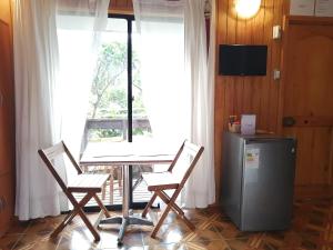 uma sala de jantar com uma mesa e 2 cadeiras e uma janela em Tuava Lodge em Hanga Roa