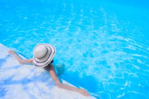 kobieta w kapeluszu leżąca w basenie w obiekcie Pura Villa- Buganvillas Ayamonte w mieście Ayamonte