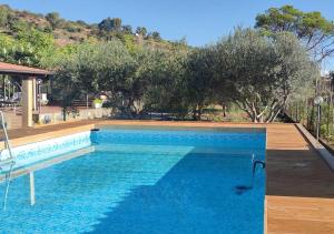 a large swimming pool with blue water and trees at Peri Peri Etna Guest House in Montargano
