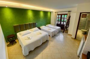 a room with three beds and a green wall at Catavento da Pipa in Pipa
