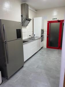 cocina con nevera y puerta roja en piso acogedor con encanto, en Navas del Rey