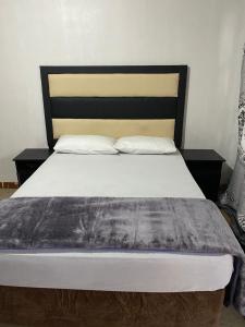Soweto Towers Guest Accommodation في سويتو: غرفة نوم مع سرير مع اللوح الأمامي الأسود والوسائد البيضاء