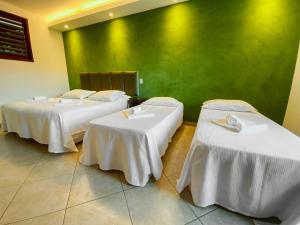 two beds in a room with white tablecloths at Catavento da Pipa in Pipa