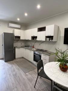 a kitchen with white cabinets and a table and a refrigerator at La Casa di Giò - Free Space n26 in Nicolosi