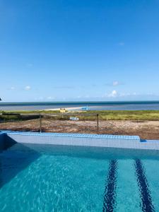 a swimming pool with a view of the beach at Pousada Dotô Sonhadô Beach in Ponta de Pedras