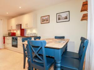 a kitchen with a wooden table and blue chairs at 2 Old Talbot Cottages in Lostwithiel