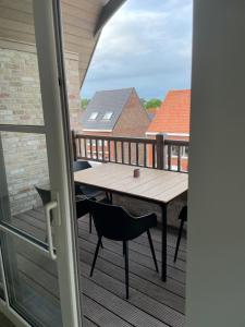 a deck with a table and chairs on a balcony at Vakantieverblijf De Munt in Oudenburg