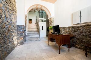 a hallway with a stone wall and a desk with a computer at Harmonia Home Capitello in Capitello
