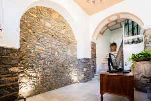 an office with a stone wall and a desk with a computer at Harmonia Home Capitello in Capitello