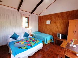 a bedroom with two beds and a television in it at Tuava Lodge in Hanga Roa