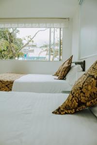 two beds in a white room with a window at Hotel Parque Reservado in Pasto