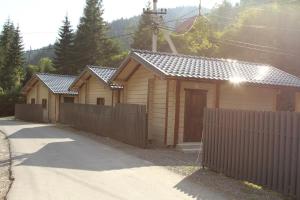 eine Reihe kleiner Holzhäuser mit einem Zaun in der Unterkunft Hotel Berloga-Sinevir in Synewyrska Poljana