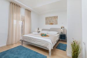 - une chambre blanche dotée d'un grand lit avec des tapis bleus dans l'établissement Pula Bay View apartment, à Pula