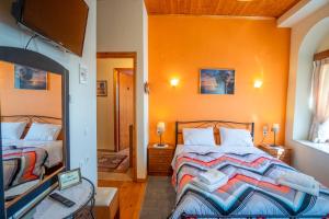 1 dormitorio con 2 camas, paredes de color naranja y espejo. en Gkoura hotel, en Sirako