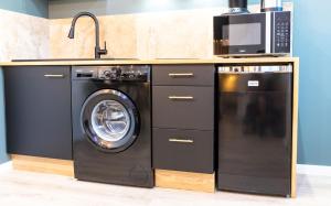 uma cozinha com uma máquina de lavar roupa e um micro-ondas em Le Cinq : Appartement Chic&Cosy, jardin privatif em Vesoul