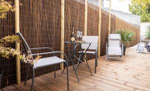 um pátio com 2 cadeiras e uma mesa com copos de vinho em Le Cinq : Appartement Chic&Cosy, jardin privatif em Vesoul