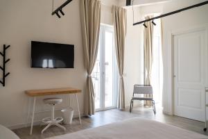 a bedroom with a desk and a television on a wall at Blanco - MAGNIFICENT B&B Altamura in Altamura