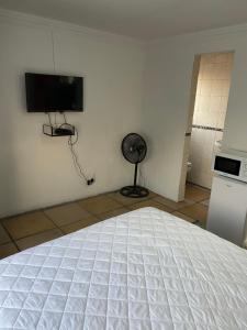 Soweto Towers Guest Accommodation في سويتو: غرفة نوم بسرير ابيض وتلفزيون على الحائط