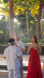 Una donna con un vestito rosso in piedi accanto a due uomini di Maya Tulum By G Hotels a Tulum