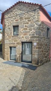a stone building with two windows on the side of it at O Cantinho da Penetra AL in Santar