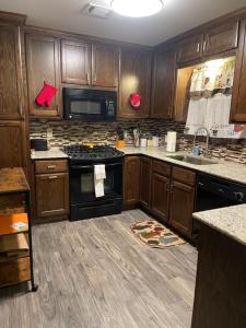 a kitchen with wooden cabinets and a black stove top oven at Comfy 3 Bed 2 Bath EZ Access To Santa's Wonderland in College Station
