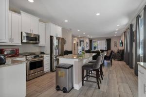 a large kitchen with white cabinets and bar stools at 451-Luxury Villa wMovie Theater and Arcade in Orlando