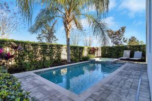 a swimming pool with two chairs and a palm tree at 451-Luxury Villa wMovie Theater and Arcade in Orlando