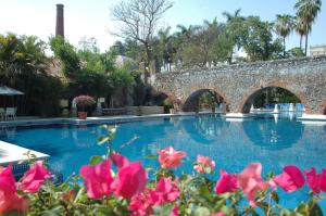 - une piscine avec un pont en pierre et des fleurs roses dans l'établissement Hotel Hacienda Vista Hermosa, à Tequesquitengo