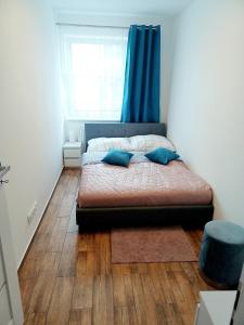 a bedroom with a bed with a blue curtain and a window at AJP Apartament Szczecin Dąbie in Szczecin