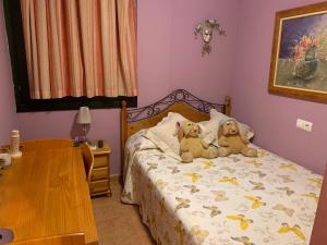 2 ours en peluche assis sur un lit dans une chambre dans l'établissement Vivienda en Costa Narejos, à Los Alcázares