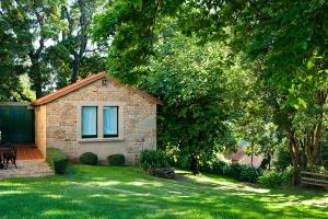 una piccola casa in mattoni in un cortile con erba verde di Complejo Turístico Rural A TORRE DE LAXE a Laxe