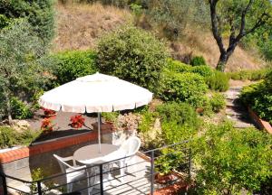 a table and chairs with an umbrella in a garden at La Collina del Melograno in Sinalunga