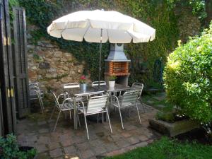 una mesa y sillas bajo una sombrilla en un patio en CA`L MOSSEN, en Sant Joan de les Abadesses