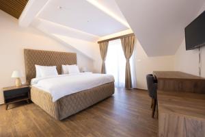 a bedroom with a bed and a tv and a window at Hotel Castello in Prizren