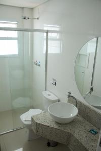 a bathroom with a sink and a toilet and a mirror at Hotel Seville Comfort in Telêmaco Borba