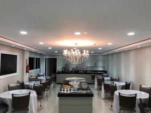 a dining room with tables and chairs and a chandelier at Hotel Seville Comfort in Telêmaco Borba