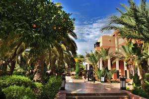 une cour avec des palmiers et un bâtiment dans l'établissement Mövenpick Hotel Mansour Eddahbi Marrakech, à Marrakech