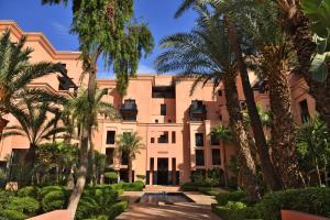 un bâtiment avec des palmiers en face de celui-ci dans l'établissement Mövenpick Hotel Mansour Eddahbi Marrakech, à Marrakech