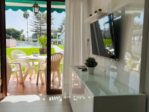 a living room with a tv and a table with chairs at Apartamentos Los Balandros by SunHousesCanarias in Maspalomas