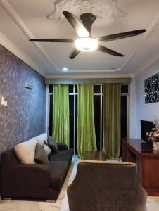 a living room with a ceiling fan and green curtains at Glory beach resort private apartment in Port Dickson