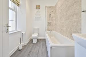 a bathroom with a toilet and a tub and a sink at The Falstone Apartment in Torquay