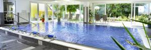 a large pool with blue water in a building at Familienhotel Steindl in Millstatt