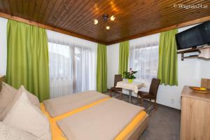 a bedroom with green curtains and a table with a bed at Pension Montana in Wagrain